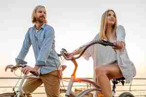 Kostenloses Foto frau und mann in der liebe, die auf fahrrädern am sonnenuntergangsmeer reist