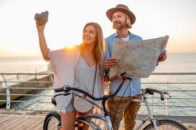 Frau und Mann in der Liebe, die auf Fahrrädern am Sonnenuntergangsmeer reist