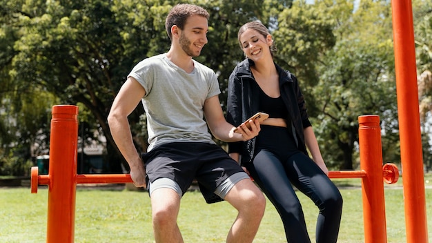 Frau und Mann mit Smartphone im Freien während des Trainings