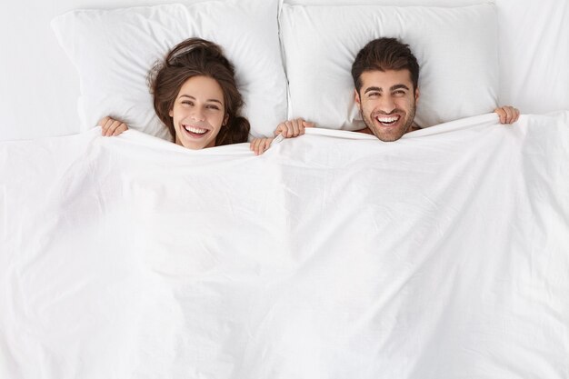 Frau und Mann sitzen in der Draufsicht des Bettes