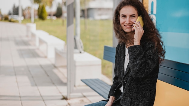 Kostenloses Foto frau wartet auf den bus und spricht am telefon