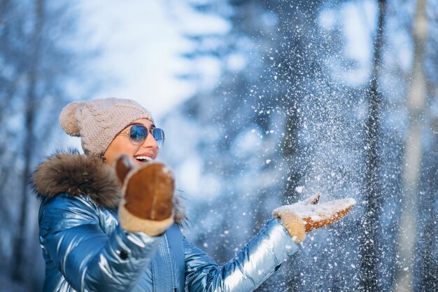 Frau weht Schnee von Handschuhen