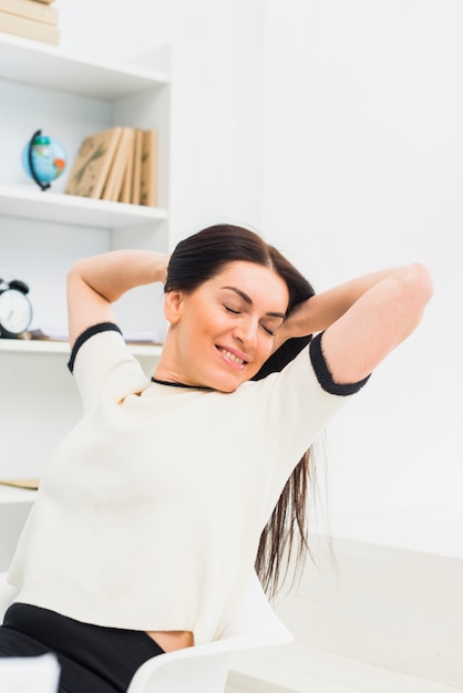 Frau, welche die Arme sitzen auf Stuhl ausdehnt