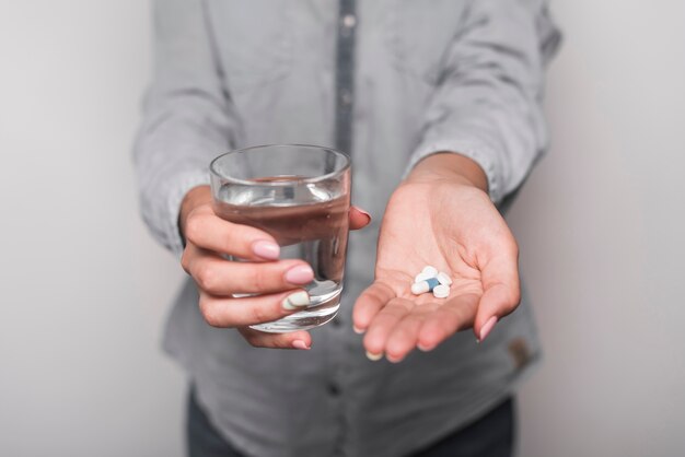 Frau, welche die Medizin hält Glas Wasser nimmt