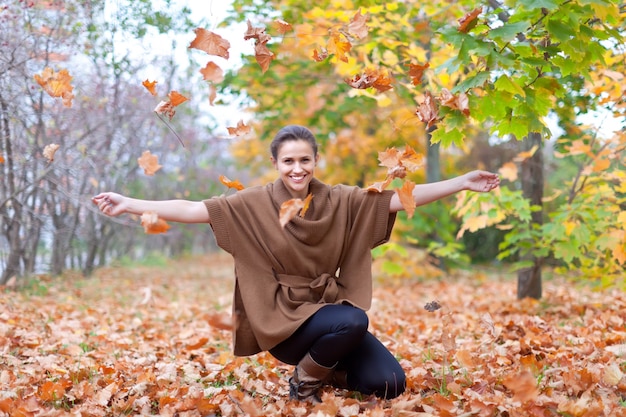 Frau wirft herbstblätter