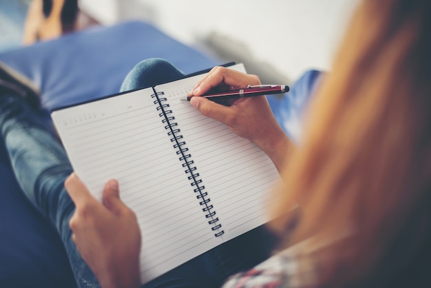 Frau writting in einem notebook auf der couch