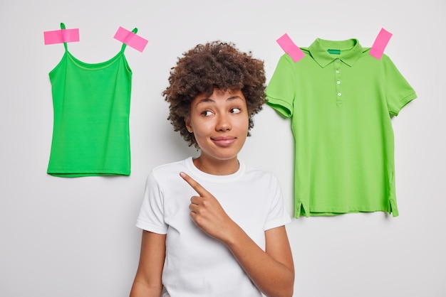 Frau zeigt weg zeigt grüne Freizeitkleidung, die in lässigen weißen T-Shirt-Posen gekleidet ist und zeigt Kleidungsstücke zum Tragen. Schau dir das an