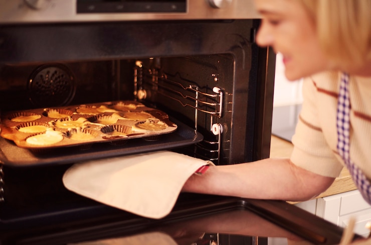 Kostenlose Foto frau zieht muffins aus dem ofen