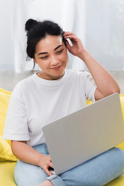 Frau zu Hause auf der Couch mit Laptop