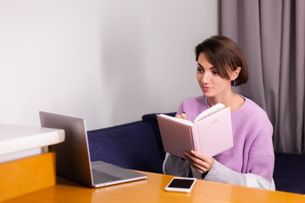 Frau zu Hause mit Notizblock Notizbuch, das über Pläne nachdenkt