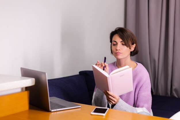 Frau zu Hause mit Notizblock Notizbuch, das über Pläne nachdenkt