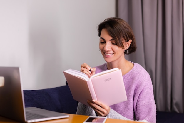 Frau zu Hause mit Notizblock Notizbuch, das über Pläne nachdenkt