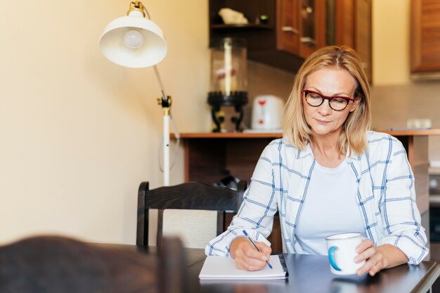 Frau zu Hause während der Quarantäne schreiben und Kaffee trinken