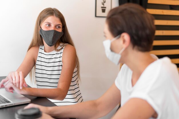 Frauen an der Terrasse mit Laptop tragende Maske