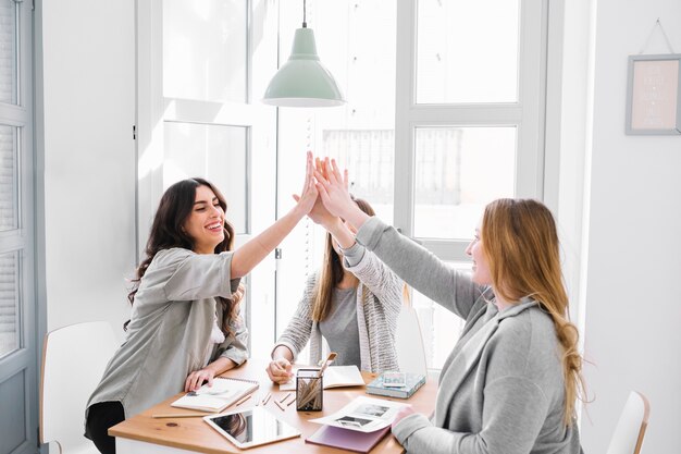 Frauen, die am Tisch hoch fiving sind