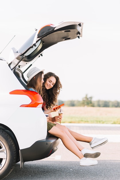 Frauen, die auf stamm des weißen autos sitzen