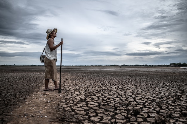 Frauen, die auf trockenem Boden und Fischereiausrüstung, globaler Erwärmung und Wasserkrise stehen