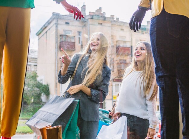 Frauen, die außerhalb des Shops stehen, Finger auf Fensteranzeige zeigend