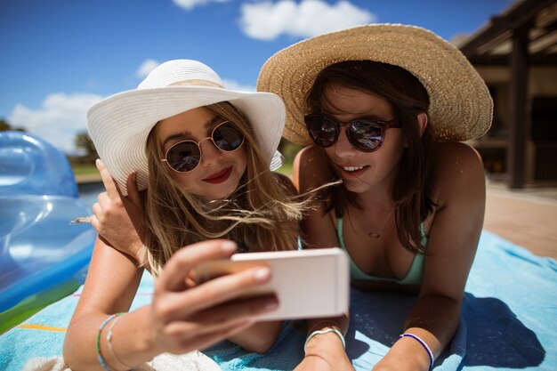 Frauen, die beim Sonnenbaden Selfie auf Handy nehmen