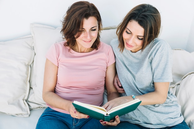 Frauen, die Buch auf nettem Sofa lesen