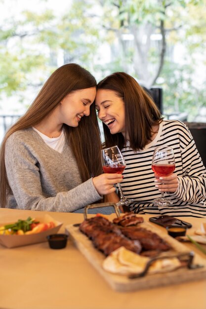 Frauen, die eine tolle Zeit bei einem Beisammensein haben, lachen und Getränke halten