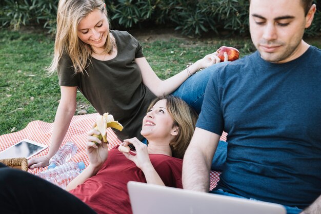 Frauen, die Früchte nahe Mann mit Laptop essen