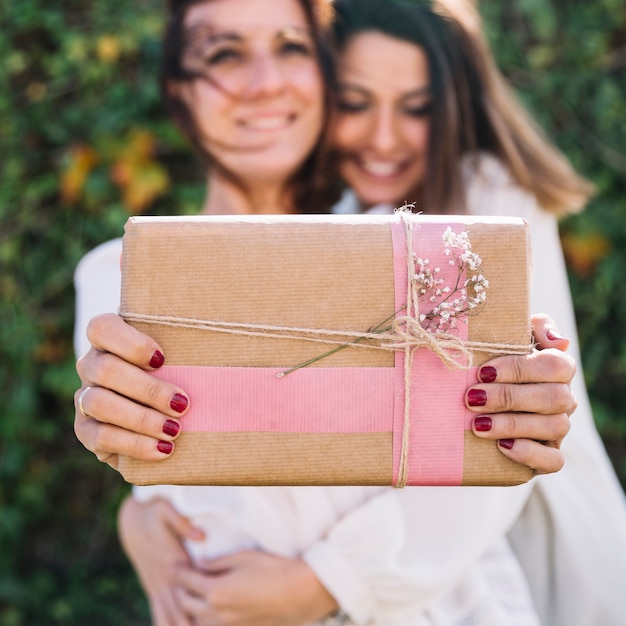Frauen, die Geschenk umarmen und zeigen