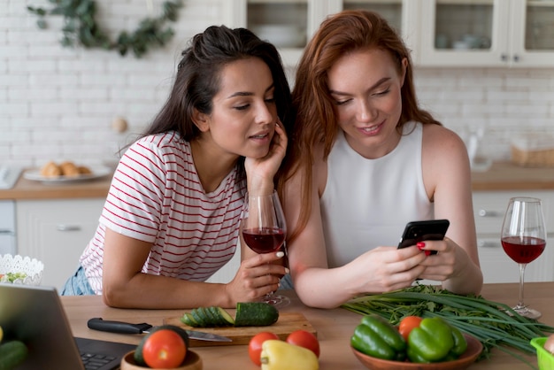 Kostenloses Foto frauen, die in der küche ins telefon schauen