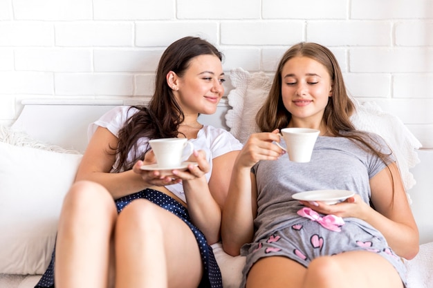 Frauen, die Kaffee auf Bett trinken