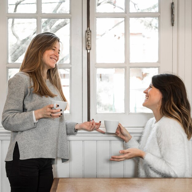 Frauen, die Kaffee nahe Fenster trinken