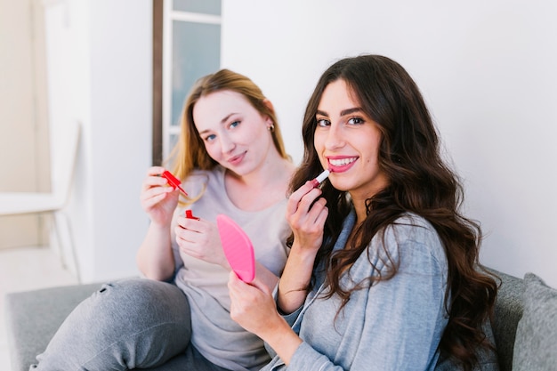 Frauen, die Kosmetik auf Couch verwenden