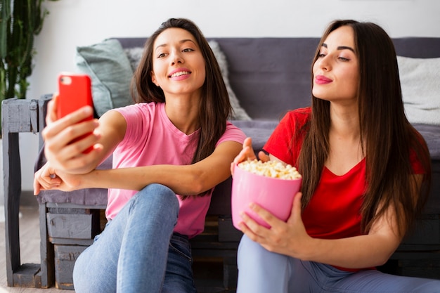 Frauen, die Pocorn essen und selfie nehmen