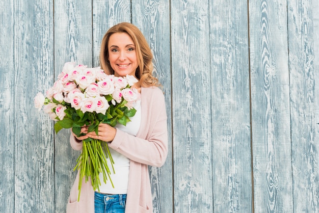 Frauen, die Rosen lächeln und anhalten