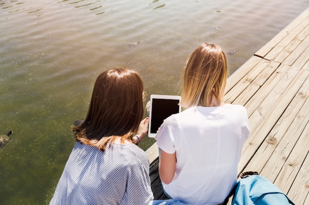 Kostenloses Foto frauen, die tablette nahe see halten