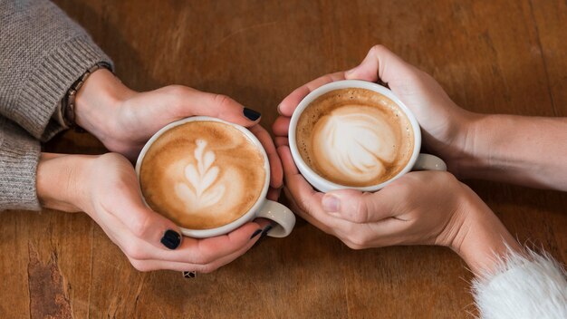 Frauen, die Tasse Kaffee auf Tabelle halten