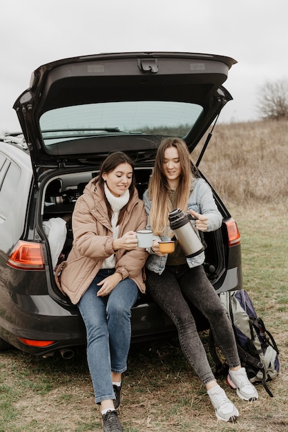 Frauen, die Tee auf Autoreisepause trinken