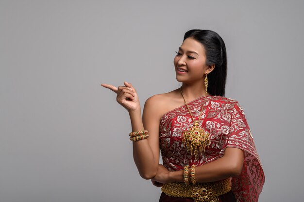 Frauen, die thailändische Kostüme tragen, die symbolisch sind und Finger zeigen