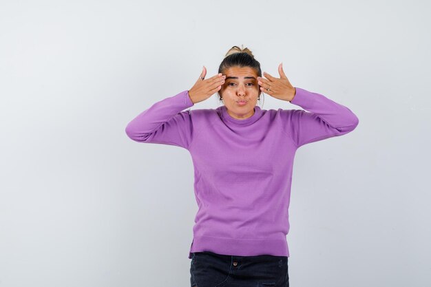 Frauen, die versuchen, die Augen mit den Händen in der Wollbluse zu bedecken und zögerlich aussehen