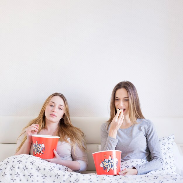 Frauen essen Popcorn im Bett