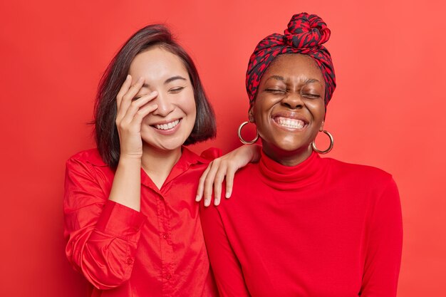 Frauen haben Spaß lachen freudig zeigen weiße perfekte Zähne tragen lässige Kleidung auf leuchtendem Rot