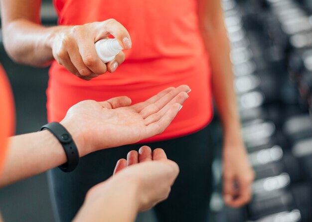 Frauen im Fitnessstudio desinfizieren ihre Hände