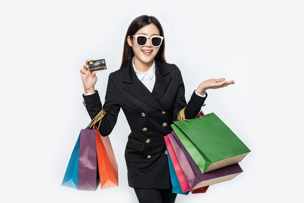 Frauen in dunklen Brillen tragen Einkäufe, tragen Kreditkarten und viele Taschen