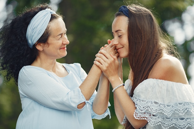 Frauen in einem Sommerwald. Dame in einem blauen Kleid. Familie posiert und umarmt.