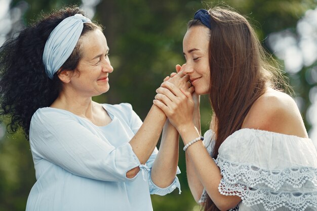 Frauen in einem Sommerwald. Dame in einem blauen Kleid. Familie posiert und umarmt.