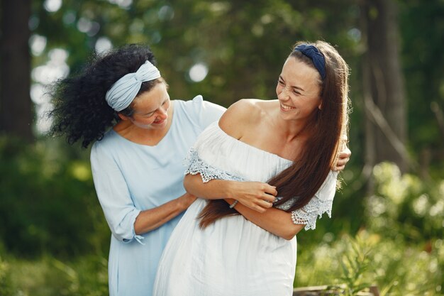 Frauen in einem Sommerwald. Dame in einem blauen Kleid. Familie posiert und umarmt.