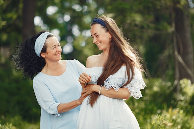 Frauen in einem Sommerwald. Dame in einem blauen Kleid. Familie posiert und umarmt.