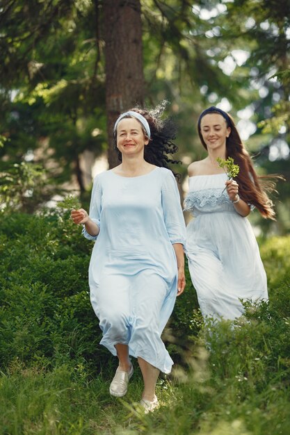 Frauen in einem Sommerwald. Dame in einem blauen Kleid. Familie posiert und umarmt.