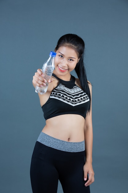 Frauen in sportbekleidung halten eine flasche trinkwasser