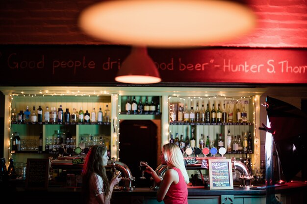 Frauen interagieren, während sie ein Glas Wein an der Theke trinken