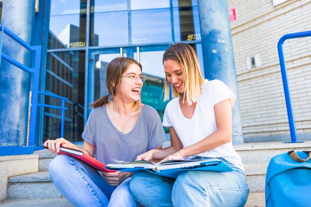 Frauen lesen Lehrbuch und lachen